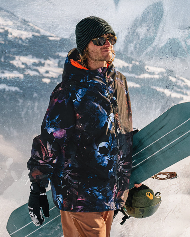 Person holding a snowboard with a mountainous background